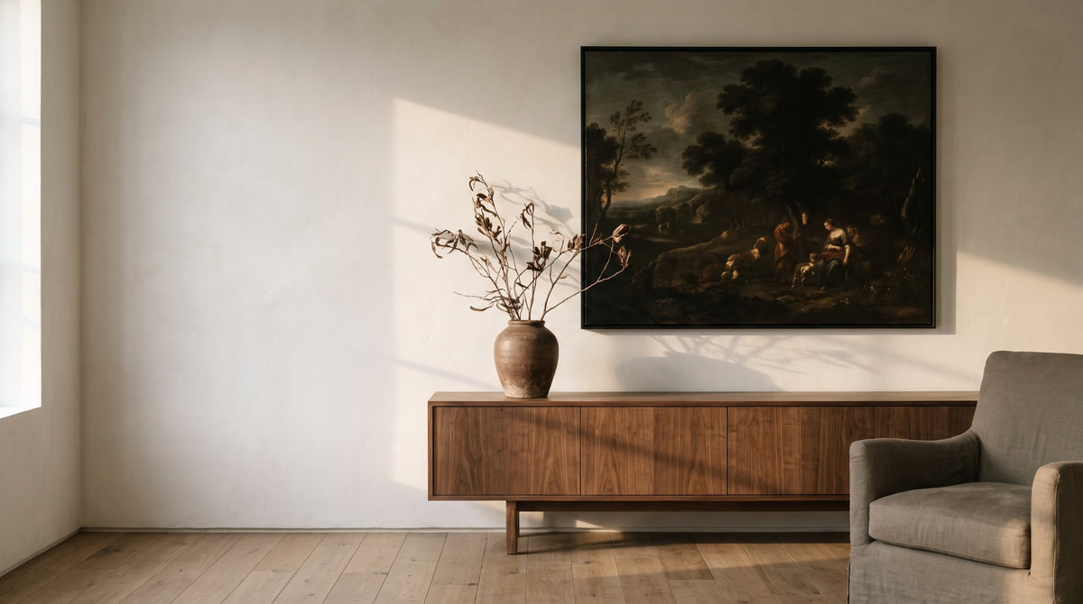 A framed classical painting above a walnut sideboard in a sunlit room