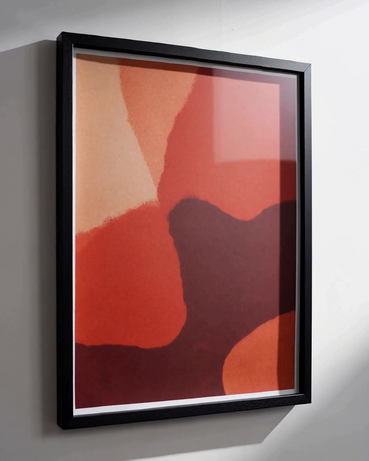 Warm red abstract print seated in the black Fuvala frame on a white wall